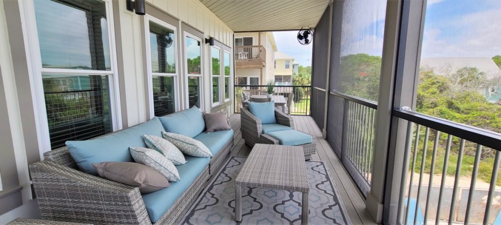 Covered and screened outside deck with room for couch, chairs, and table with seating on a custom-built home in Port St Joe, Florida.