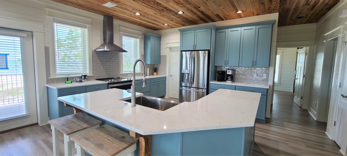 Kitchen with island, stainless steel appliances and wood ceiling.