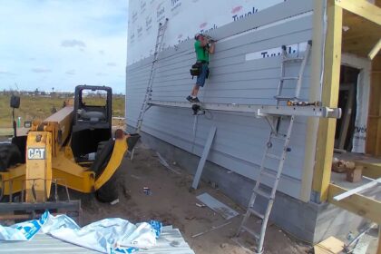 Worker on the exterior side wall of new Mexico Beach home as it's being built.