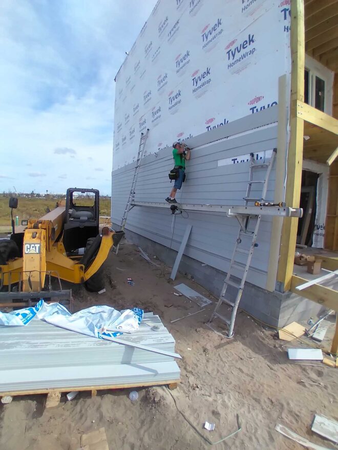 Worker on the exterior side wall of new Mexico Beach home as it's being built.