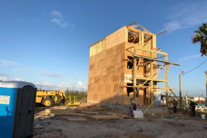 Three story new construction home shows walls up and scaffolding.