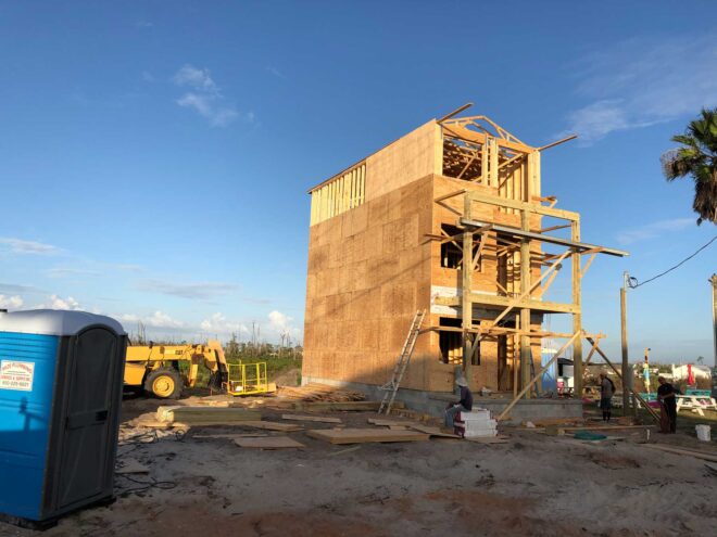 Three story new construction home shows walls up and scaffolding.